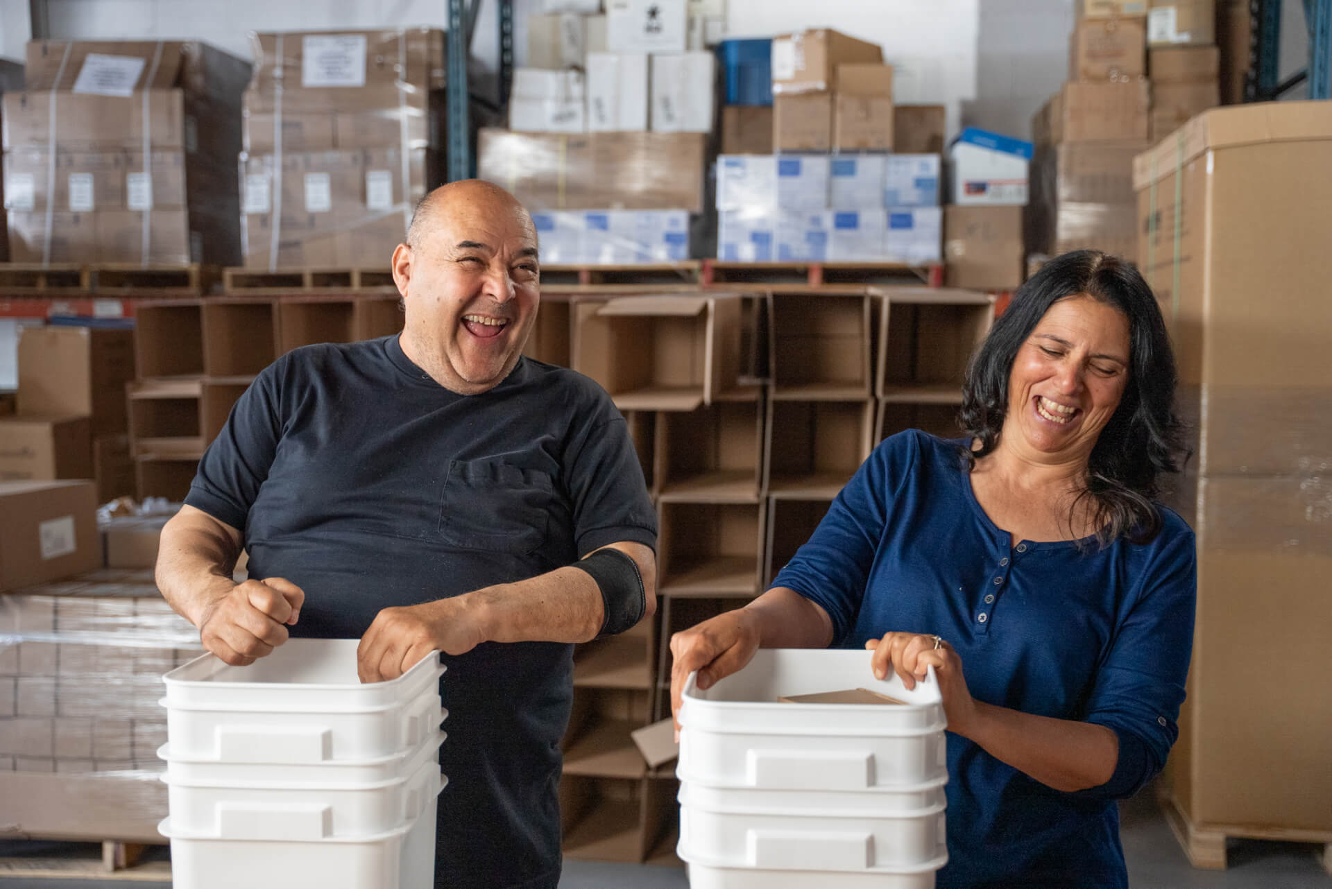 Smiling volunteers packing donation bins in a warehouse