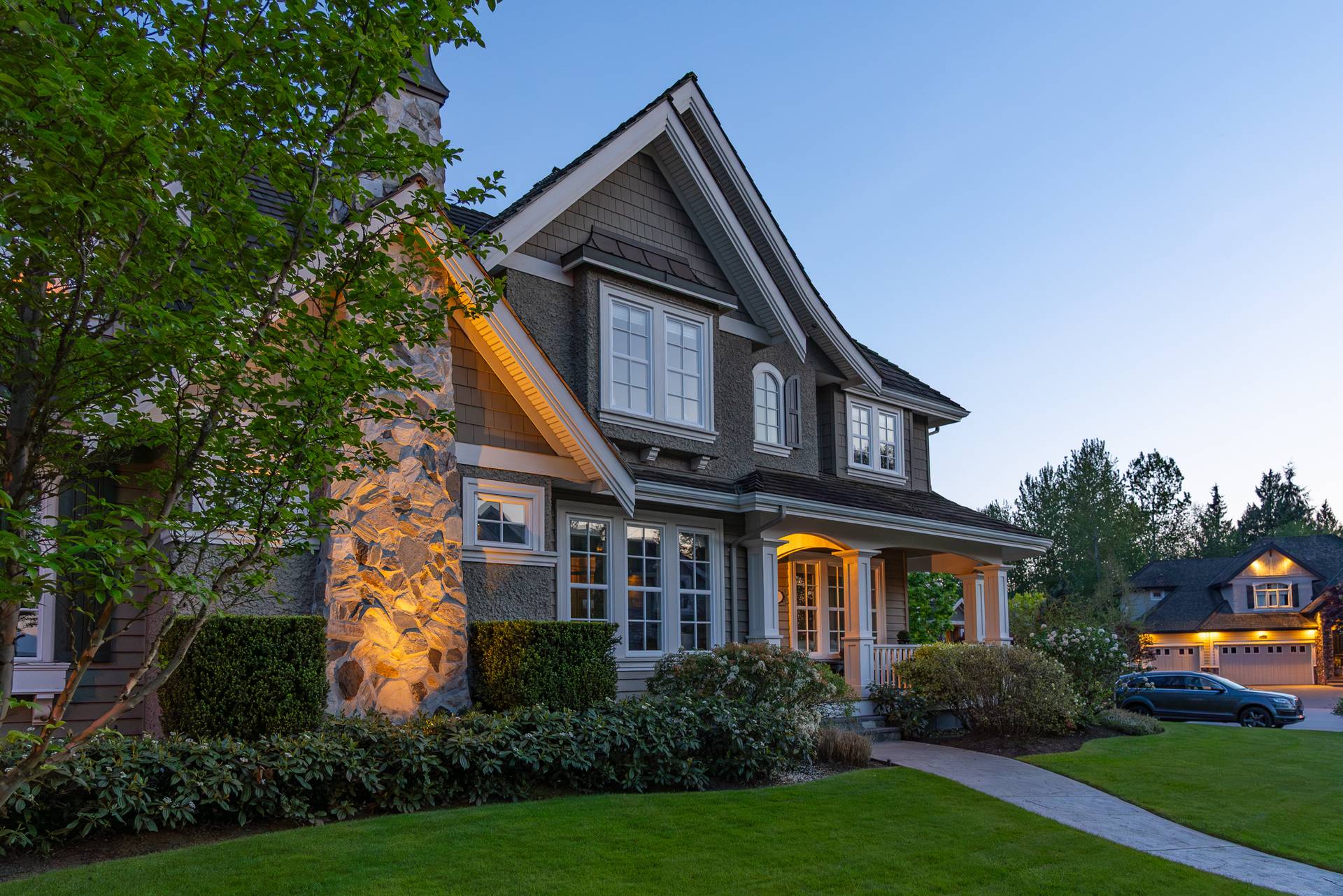 Two-storey stucco luxury house with spring blossoms at night in Vancouver